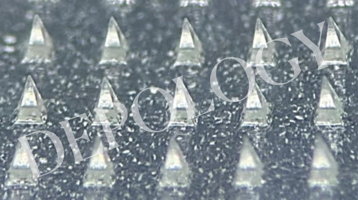 Close-up of metallic pyramid-shaped objects on a textured surface
